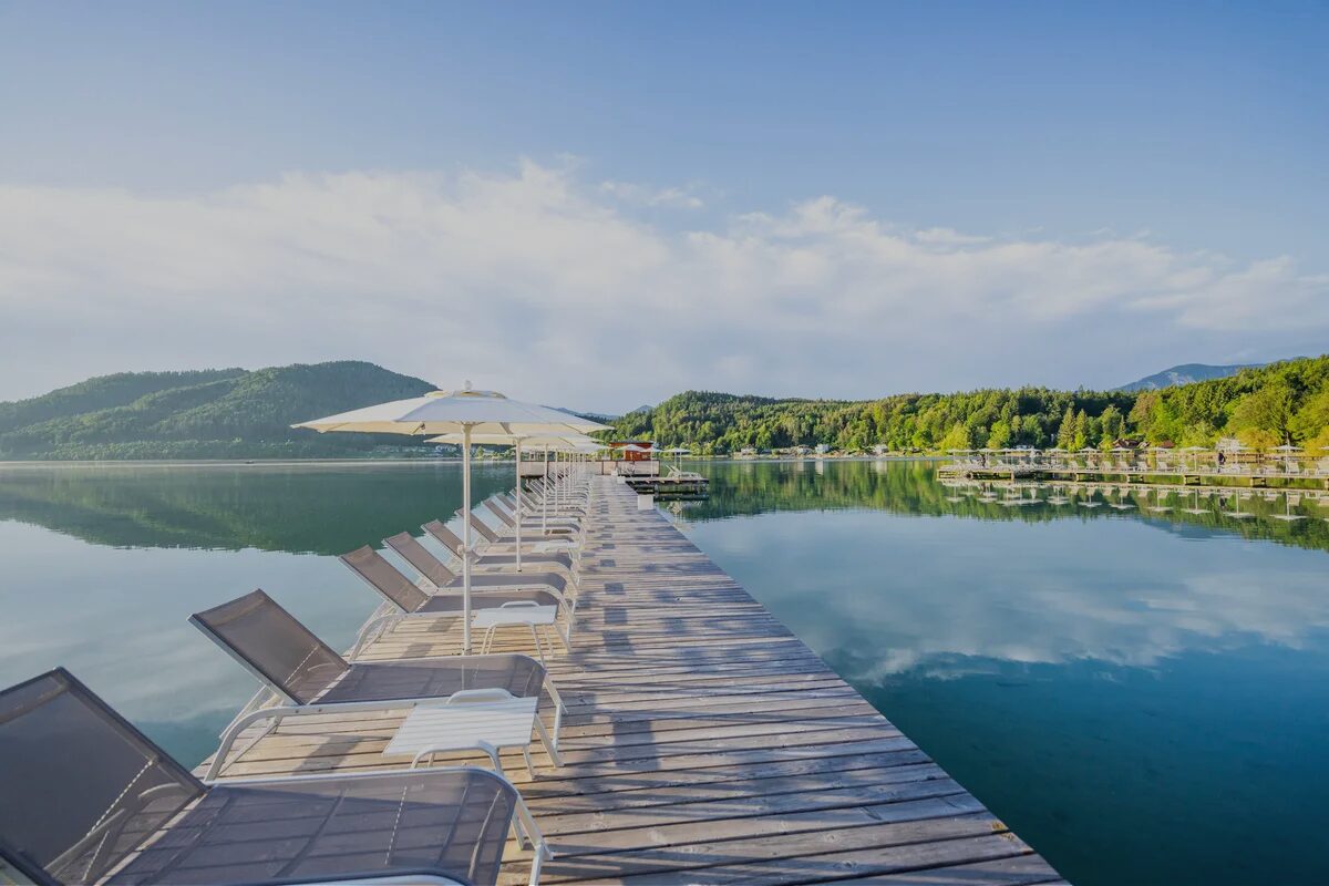 Ein Steg an einem See mit Sonnenliegen und Sonnenschirmen