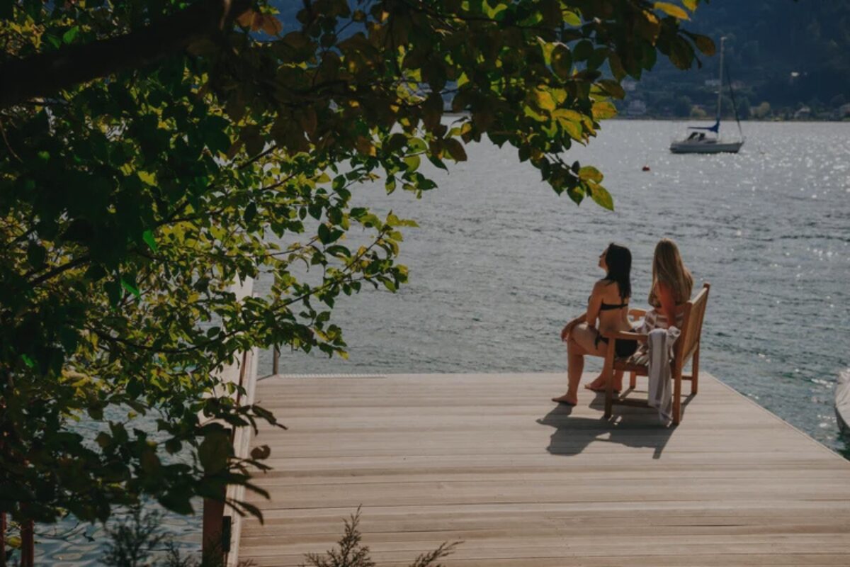 Zwei Frauen, die auf einem Steg am Wörthersee in der Sonne sitzen
