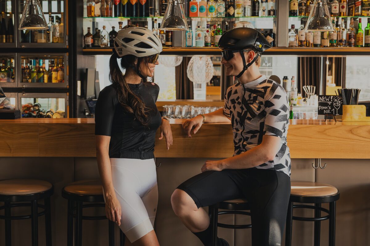 Eine Frau und ein Mann in Rad-Dressen, die an einer Hotelbar sitzen