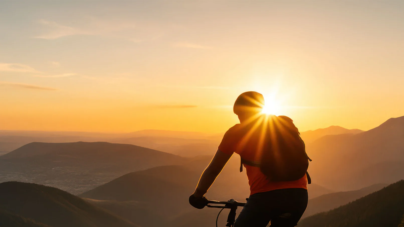 Ein Radfahrer, der über eine hügelige Landschaft blickt, im Sonnenuntergang